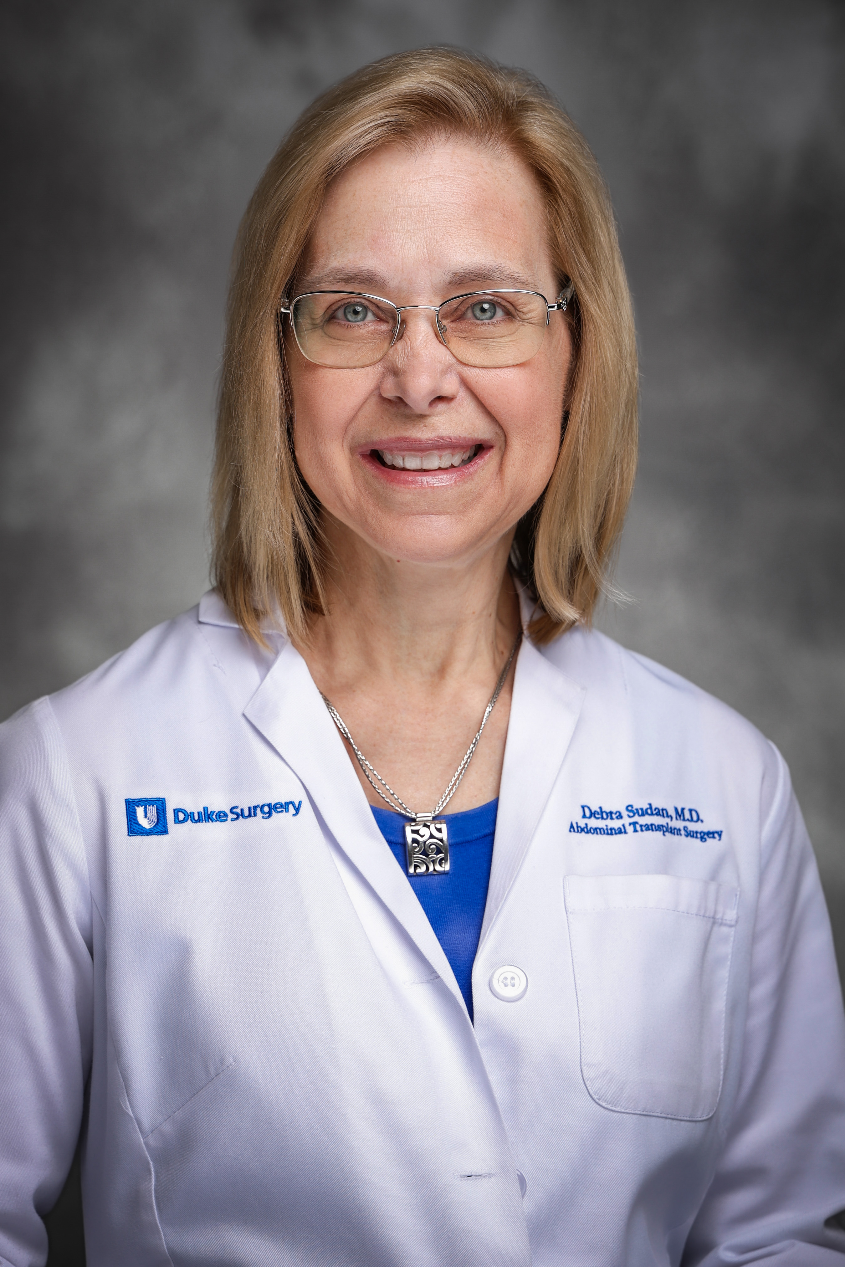 Debra Clausing Sudan's professional headshot in her medical white coat. 