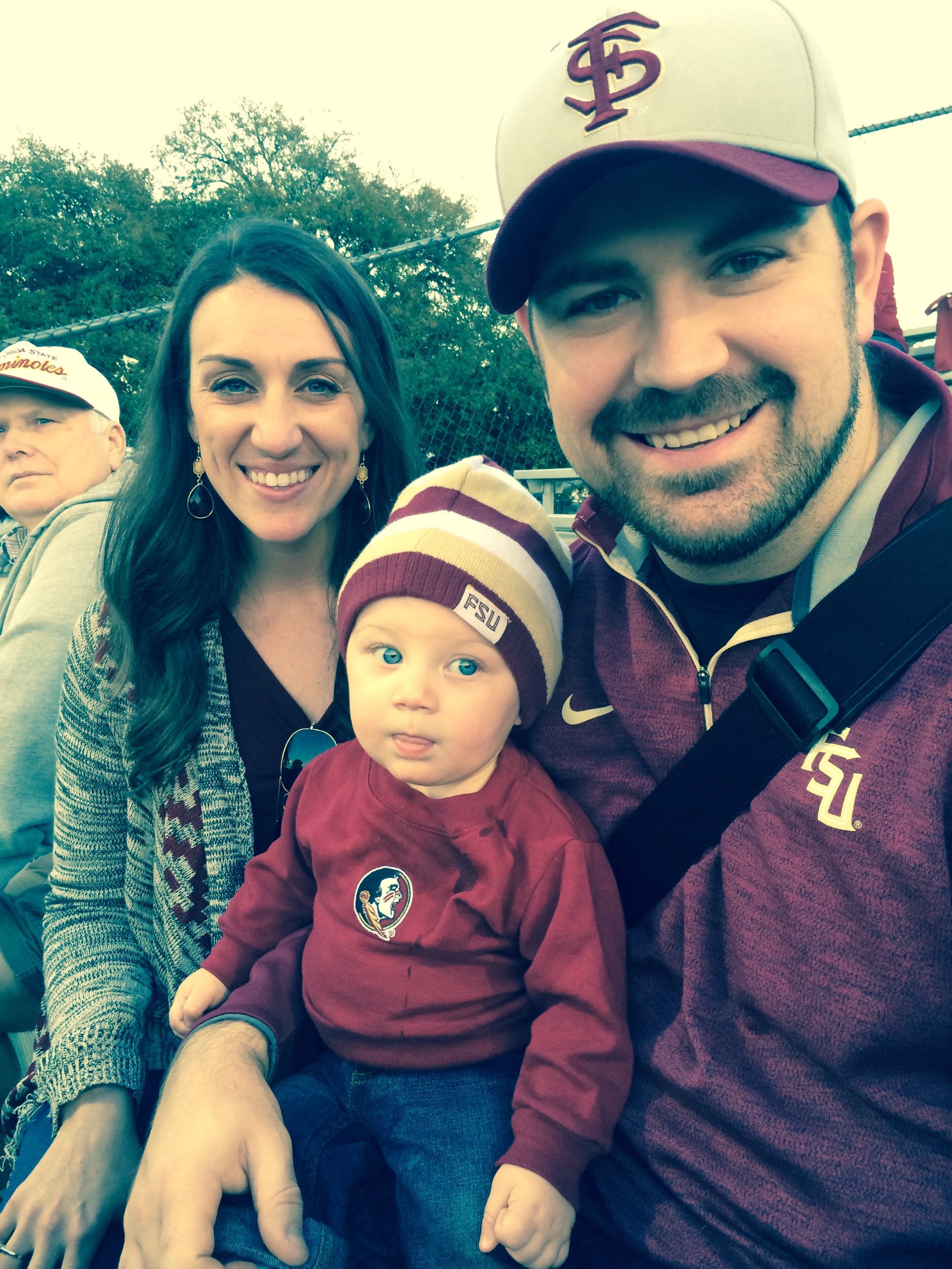 Justin Kume, his wife, and son are all wearing dark red and gold colors for Florida State. 