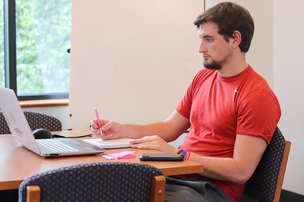 muskingum student learning remotely sitting at a table with his laptop