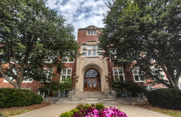 Main entrance of Montgomery Hall with magenta petunia flowers in bloom.