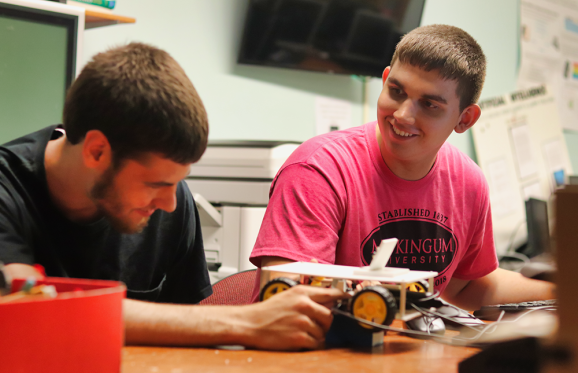 2 male students building a 3d printed remote control car that uses AI technology to drive