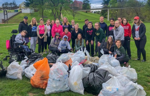 a group of students posing behind all the bags of trash that they collected