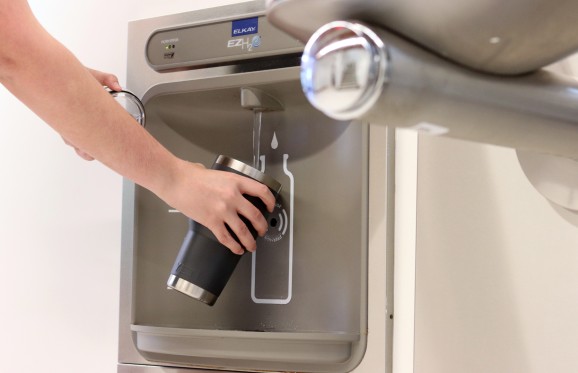 hand reaching out to fill up water bottle in a new water station