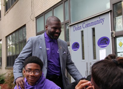 ramone davenport being carried the shoulders of one of his students outside the school he runs