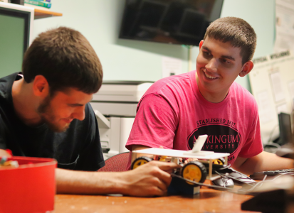 2 male students building a 3d printed remote control car that uses AI technology to drive