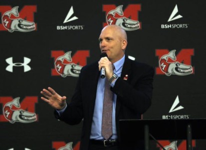 Steve Brockelbank speaking at the annual Athletics Night of Impact event, in front of a MU backdrop featuring the fighting muskies logo and their apparel sponsor's logo, under armour.