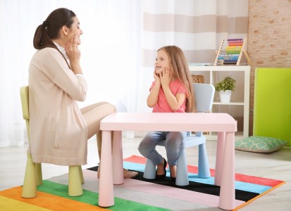 An Occupational Therapist working with a young girl at a child-friendly table.