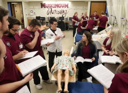 nursing class gathered around a hi fidelity simulation child dummy during class