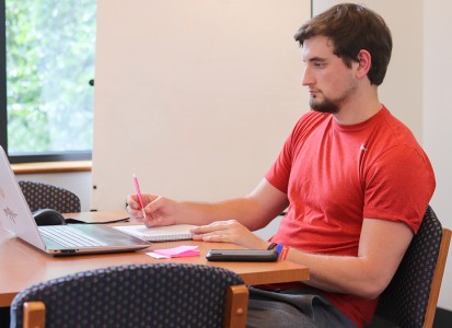 muskingum student learning remotely sitting at a table with his laptop