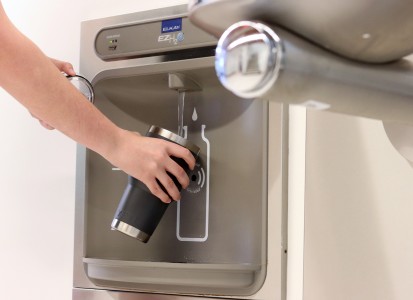 hand reaching out to fill up water bottle in a new water station